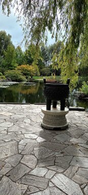 Steinterrasse mit Skulptur mit Teich im Hintergrund